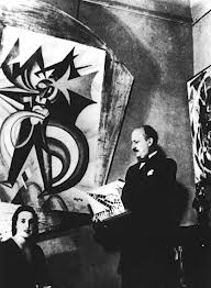 Marinetti standing and Cappa seated in front of a large Futurist painting.