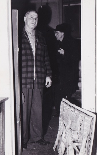 Two men visible in doorway, with Loy's construction propped against door frame