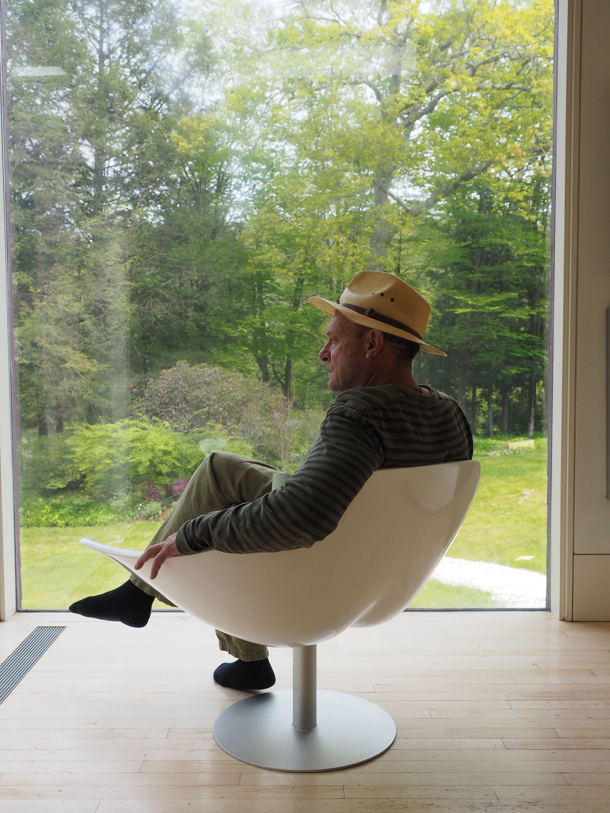 Conver sitting in a deck chair overlooking the woods behind his Maine home