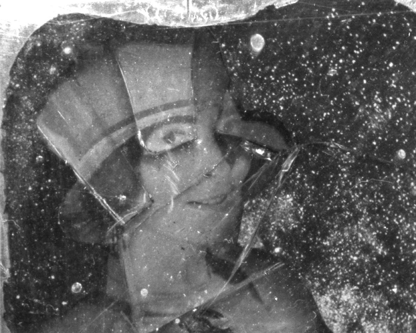 Black and white photo of Loy's face under cracked glass that highlights her right eye.