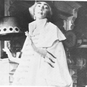 Mina Loy dressed for Blind Man's Ball in a white cape with stripes across the front