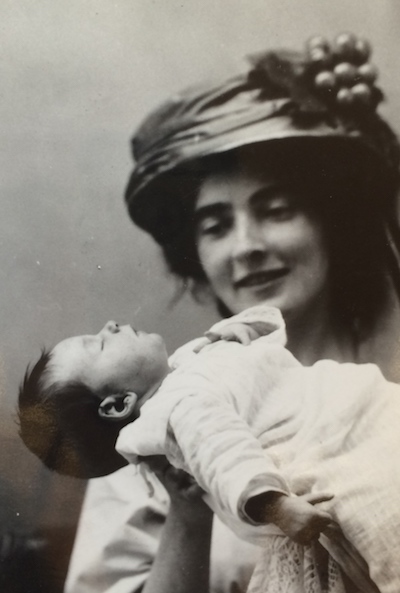 Mina Loy smiles lovingly at baby Oda, who she holds up in her hands.